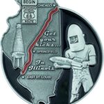 Silver-colored challenge coin. Features Route 66 map, Abraham Lincoln statue, and 