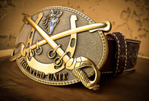 Gold-tone belt buckle depicts a rearing horse and crossed sabers. "Mounted