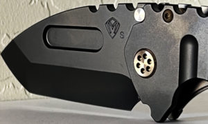Black Medford Praetorian knife. Features a textured handle, a visible pin, and a Challenge Coin USA logo.