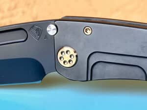 Close-up of a Medford Marauder-H knife. Dark gray titanium frame with a blue