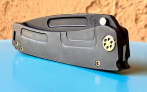 Close-up of a black Medford Marauder-H knife. Features a textured handle and gold pivot