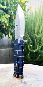 Blue and gray Medford USMC Fighter flipper knife. Visible blade and handle. Challenge Coin