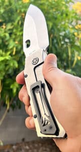 Medford TFF1 folding knife, silver blade, black handle. Held in hand against a blurred